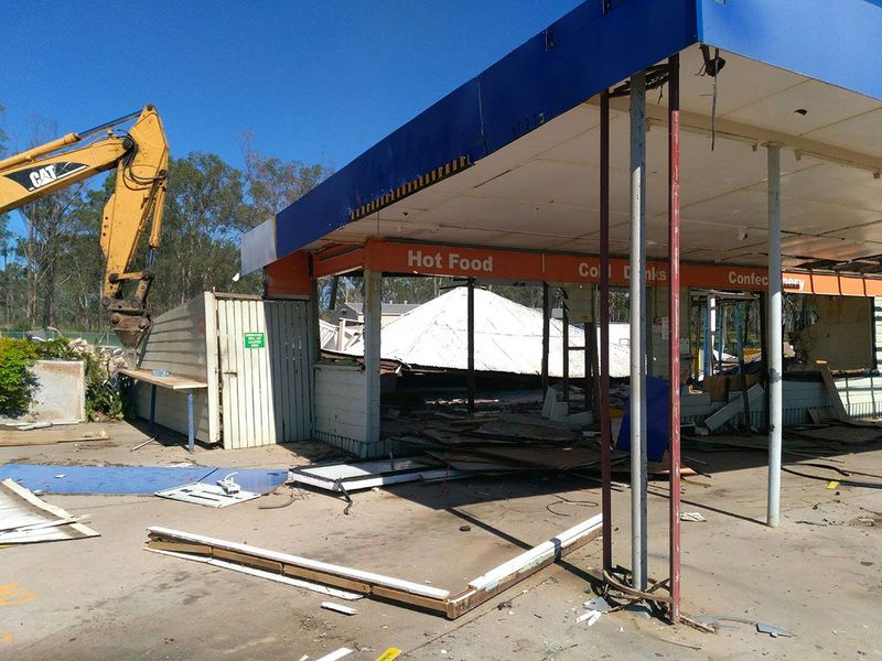 A building is being demolished with a bulldozer in the background.