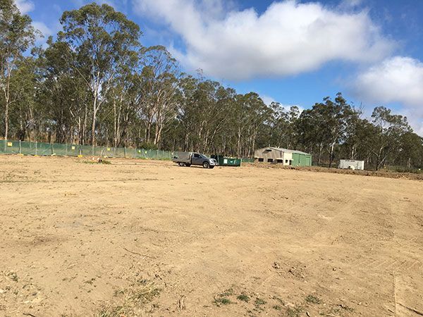 A truck is parked in the middle of a dirt field surrounded by trees.