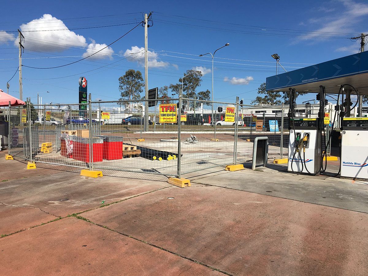 A gas station with a fence around it is being remodeled.