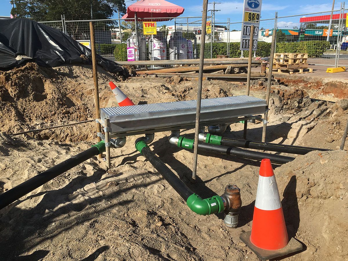 A construction site with cones and pipes in the dirt.