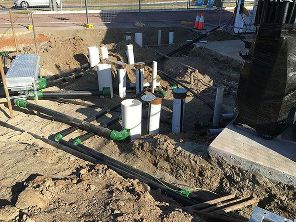 A bunch of pipes are laying in the dirt on a construction site.