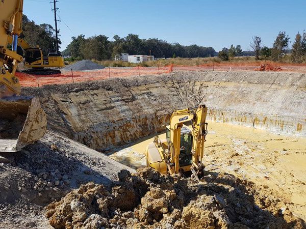 A yellow excavator is digging a hole in the dirt.