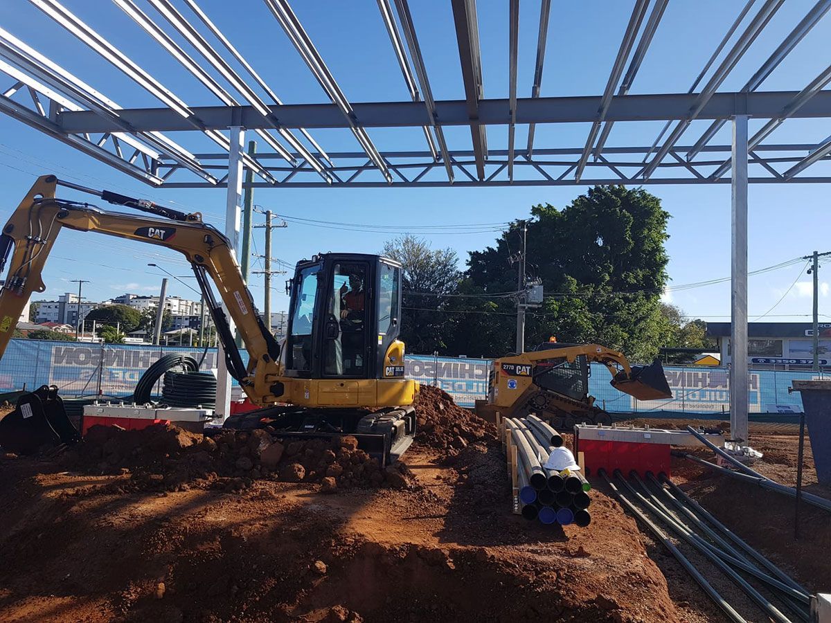 A yellow excavator is digging a hole in a construction site