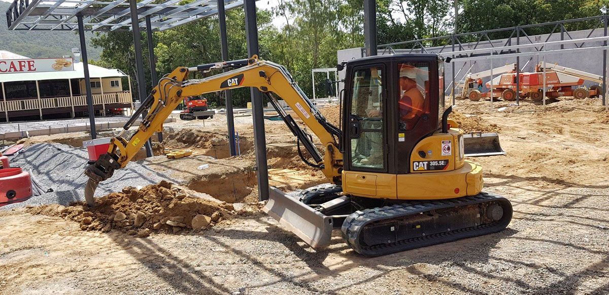 A small excavator is digging a hole in the dirt on a construction site.