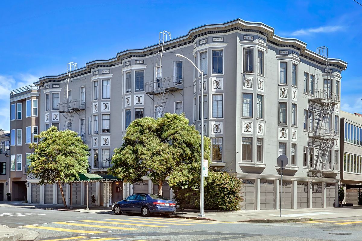 390 Bartlett- a large apartment building with a car parked in front of it .