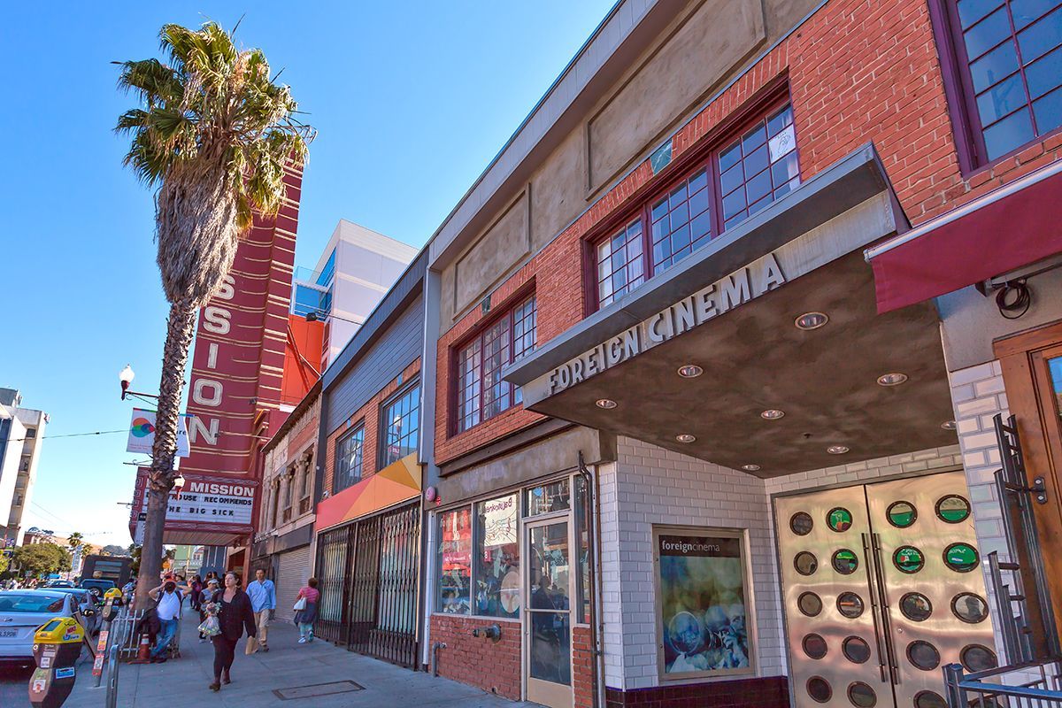 155 Bartlett- a group of people are walking down a sidewalk in front of a building that says ' bioz ' on it .