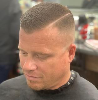 A man is getting his hair cut at a barber shop.
