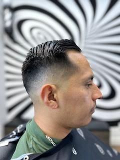 A man is getting his hair cut at a barber shop.