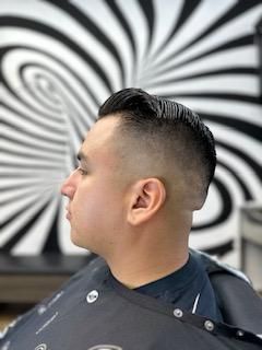 A man is getting his hair cut at a barber shop.