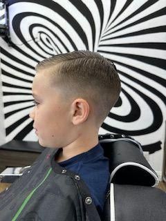 A young boy is getting his hair cut at a barber shop.