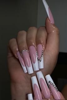A close up of a person 's hand with long pink and white nails.