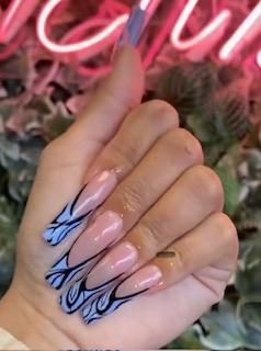 A close up of a person 's hand with long nails and a neon sign in the background.