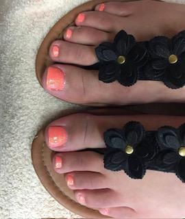 A close up of a person 's feet wearing sandals with flowers on them.