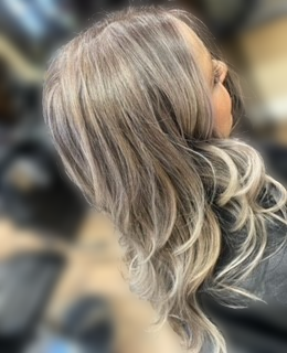A woman with long blonde hair is sitting in a chair in a salon.