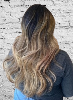 A woman with long hair is standing in front of a white brick wall.