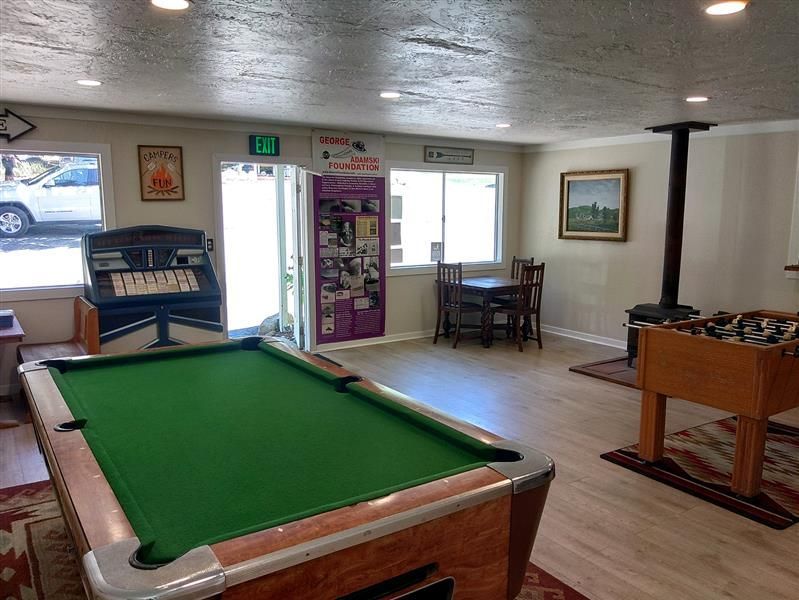 Pool table in a game room with an open door, foosball, and a jukebox.