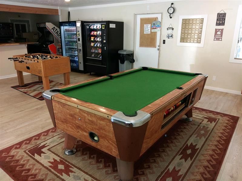 Pool table in a recreation room with foosball, vending machines, and a bulletin board.