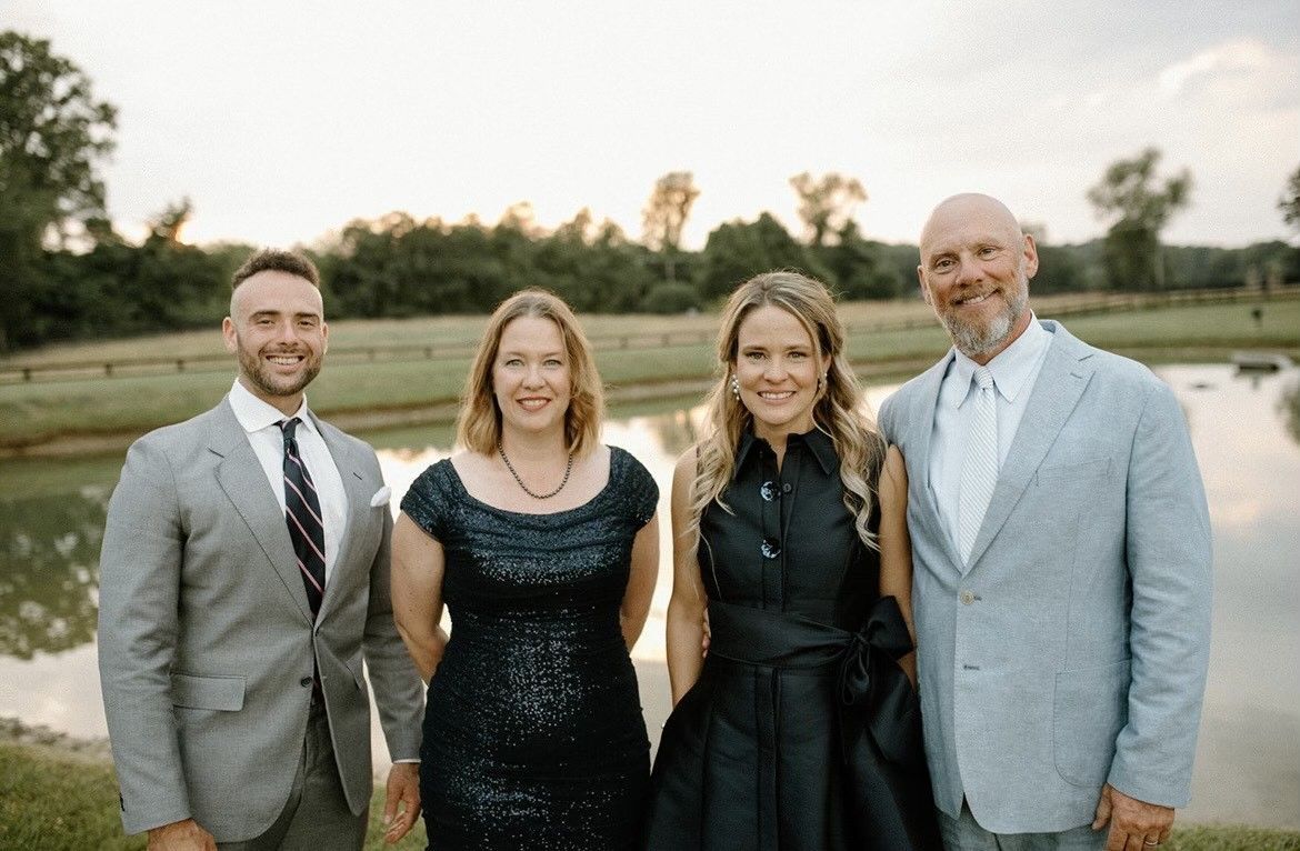 The OHS team are posing for a picture in front of a lake.