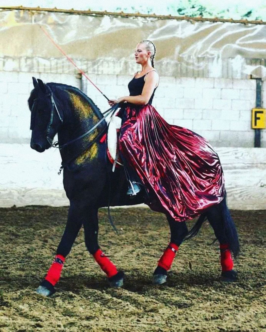 donna con un vestito rosso cavalca un cavallo nero