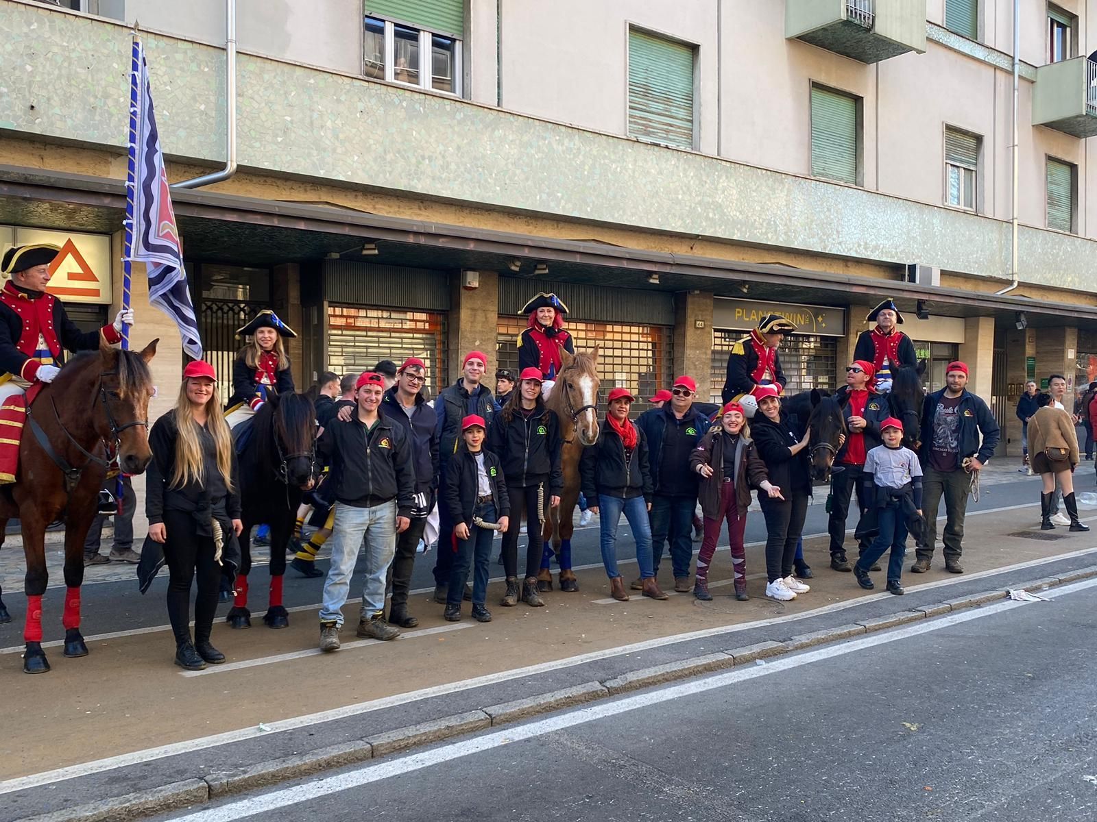 gruppo di persone in piedi sul ciglio di una strada accanto a un edificio