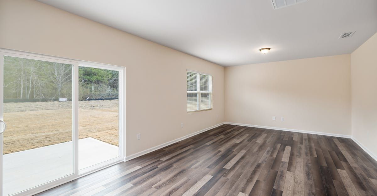 An empty living room with hardwood floors and sliding glass doors.