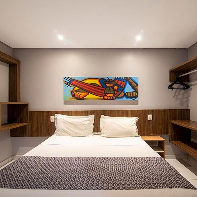 Há uma pintura na parede acima da cama no quarto. Netuanah Praia Hotel