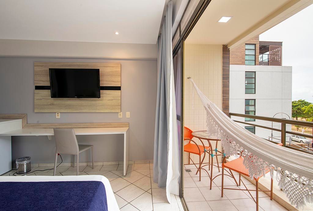 Um quarto de hotel com uma rede e uma TV de tela plana. Netuanah Praia Hotel