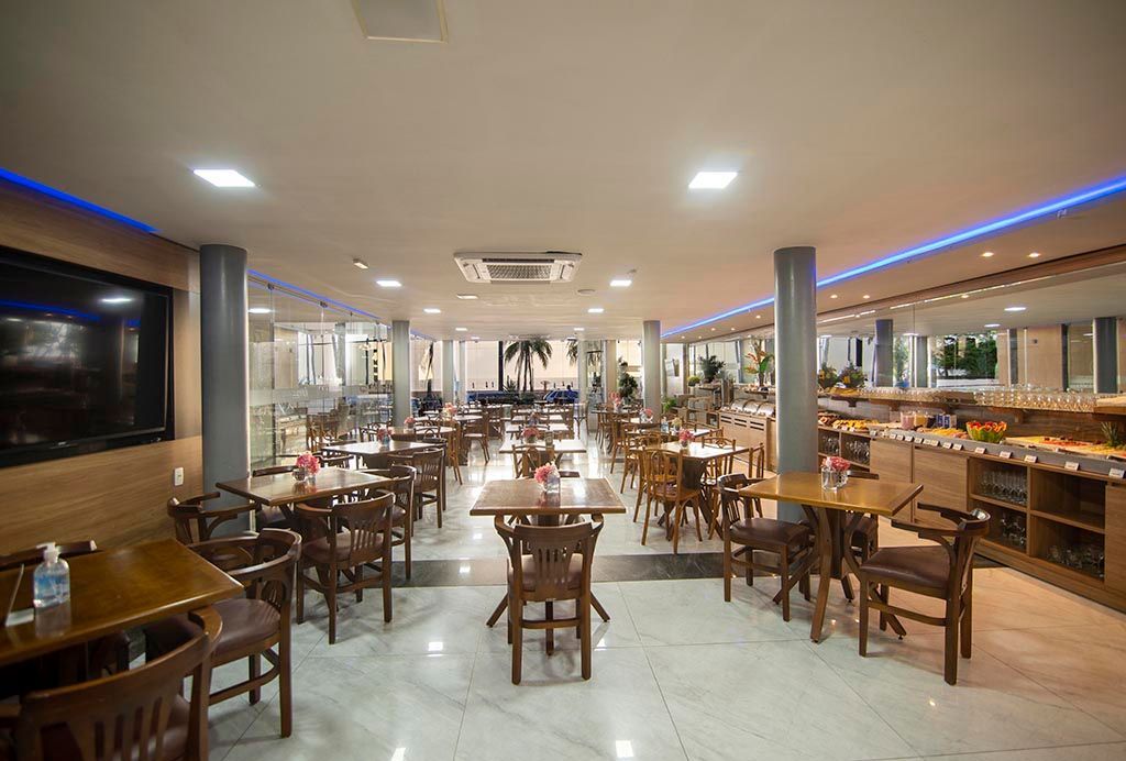 Há muitas mesas e cadeiras no restaurante. Netuanah Praia Hotel