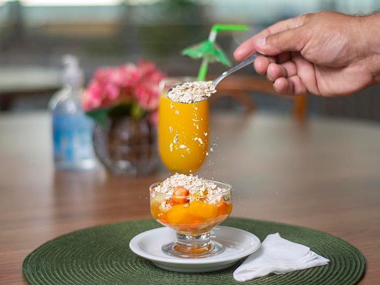 Uma pessoa está despejando suco de laranja. Netuanah Praia Hotel