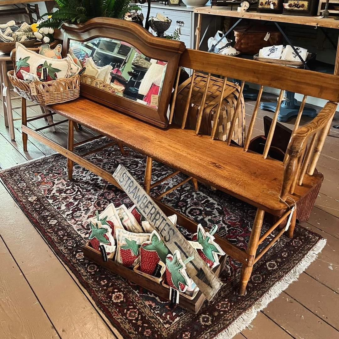 A wooden bench is sitting on a rug next to a mirror.