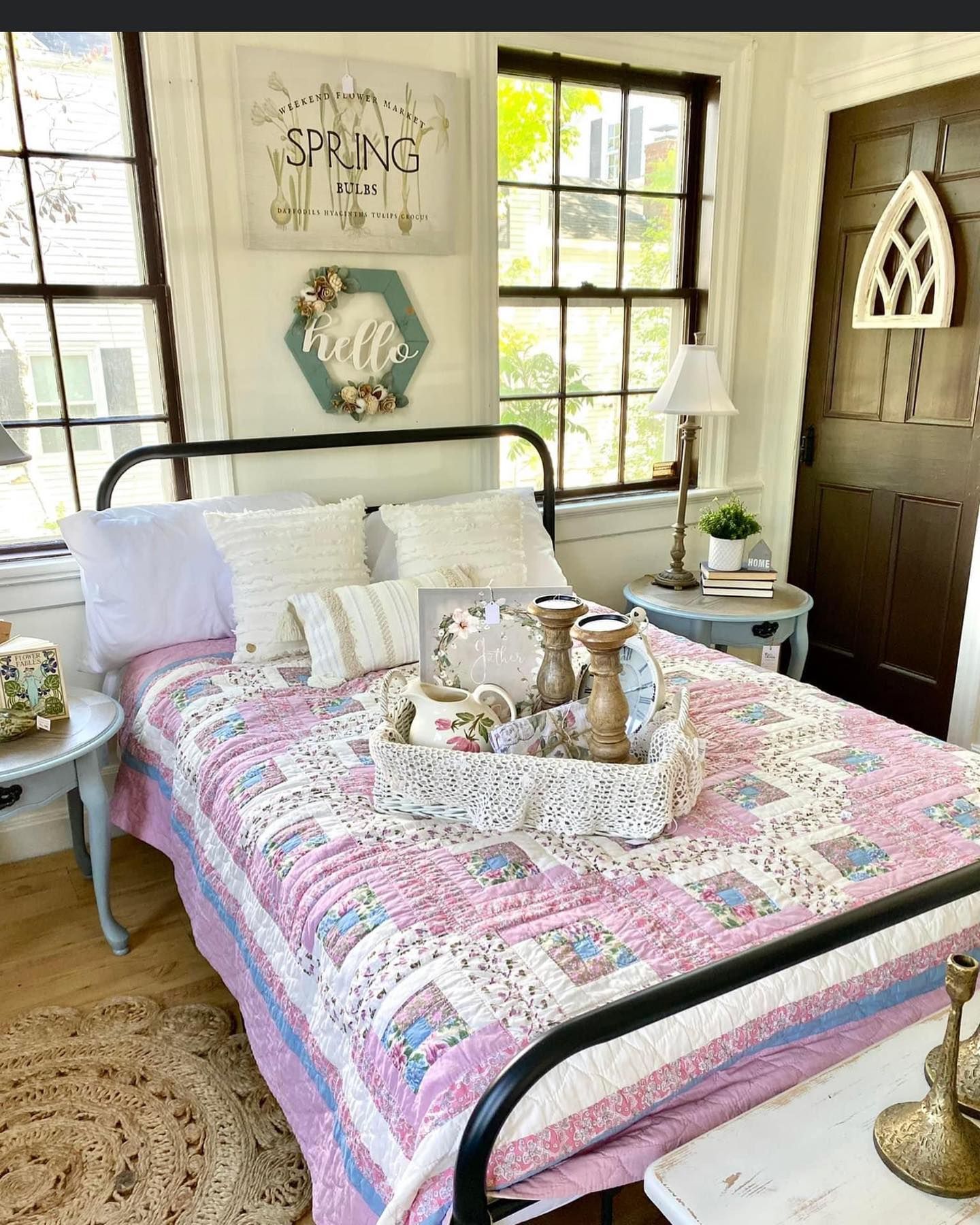 A bed with a pink quilt and a tray on it in a bedroom.
