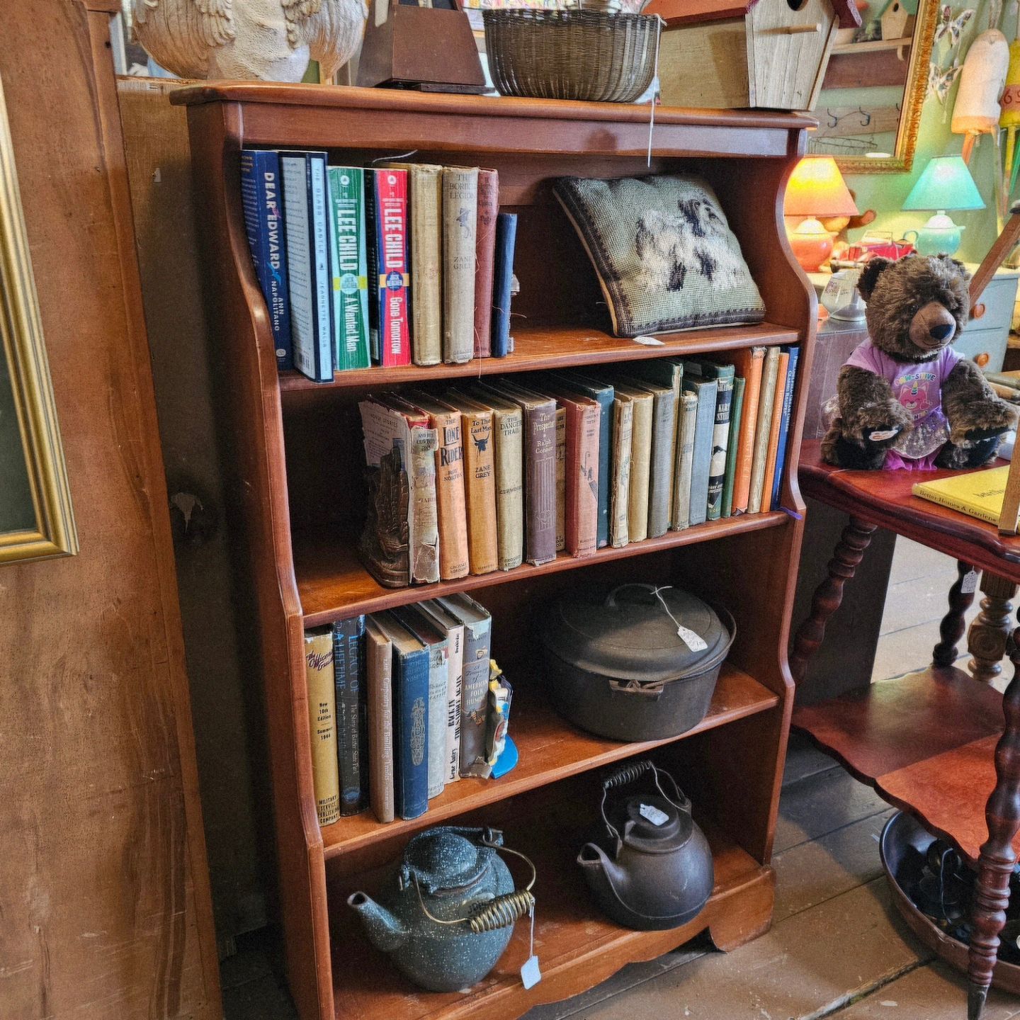A wooden bookshelf filled with books and pots