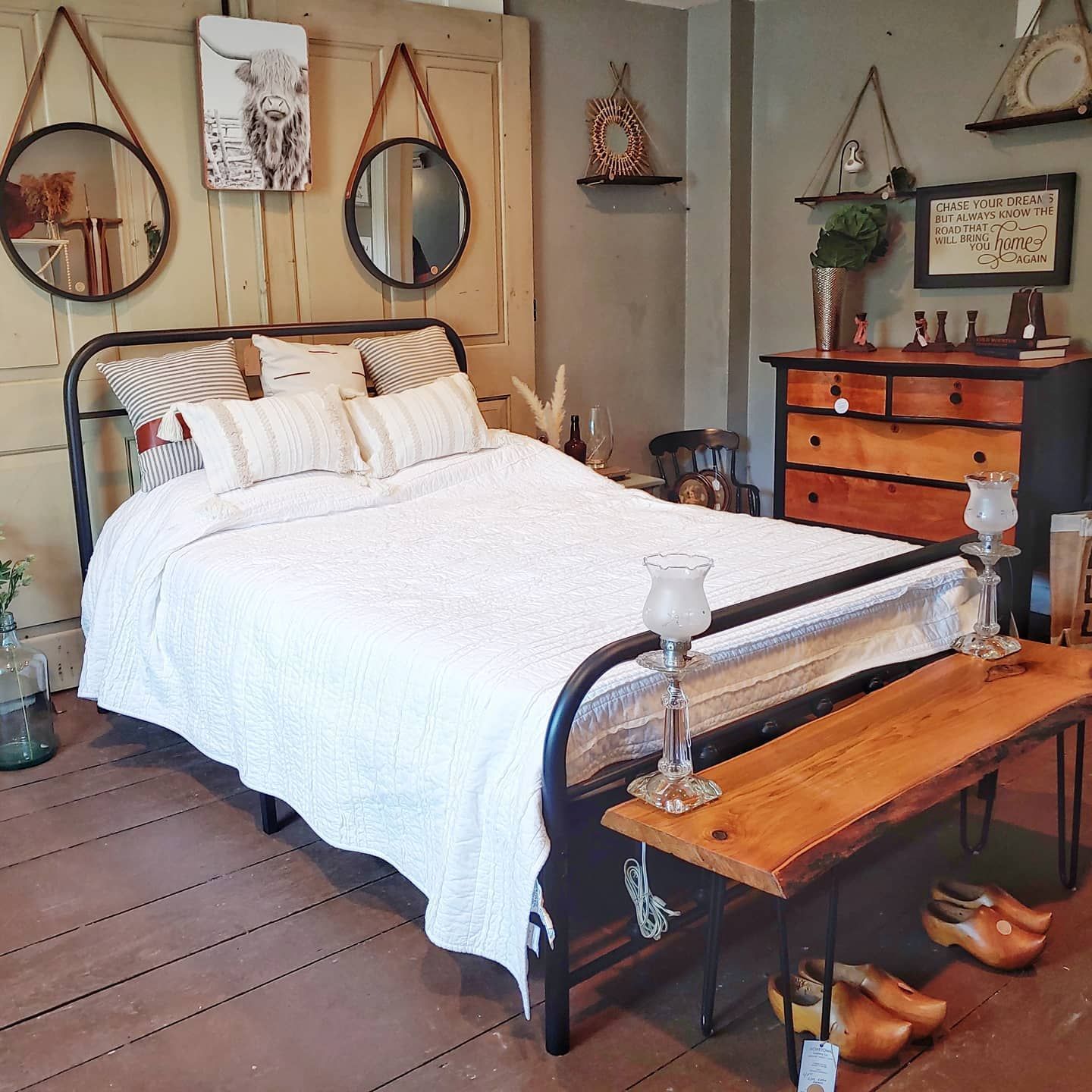 A bedroom with a bed a dresser and a bench