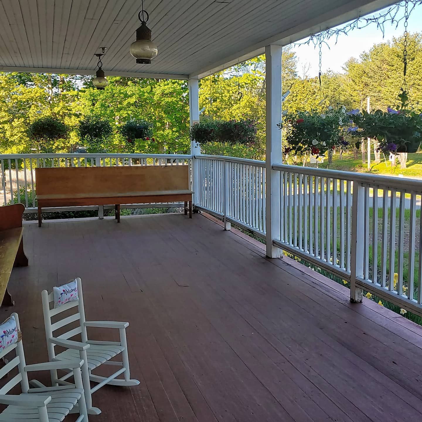 A porch with rocking chairs and a bench