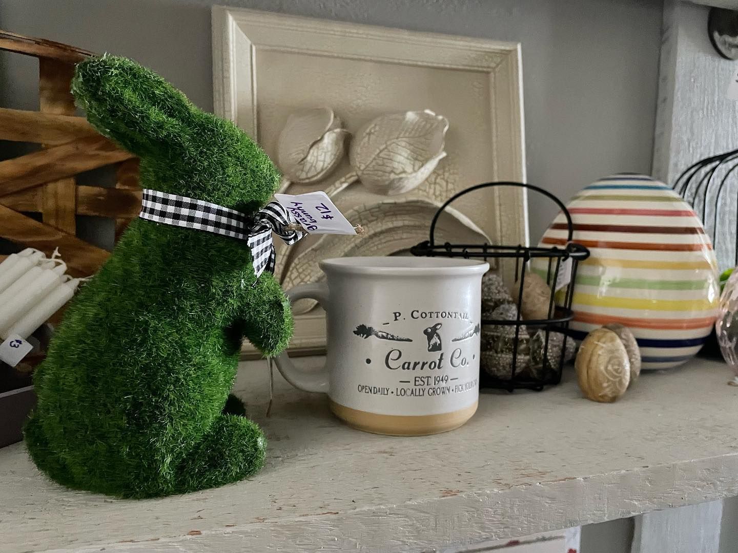 A green bunny is sitting next to a mug that says carrot on it