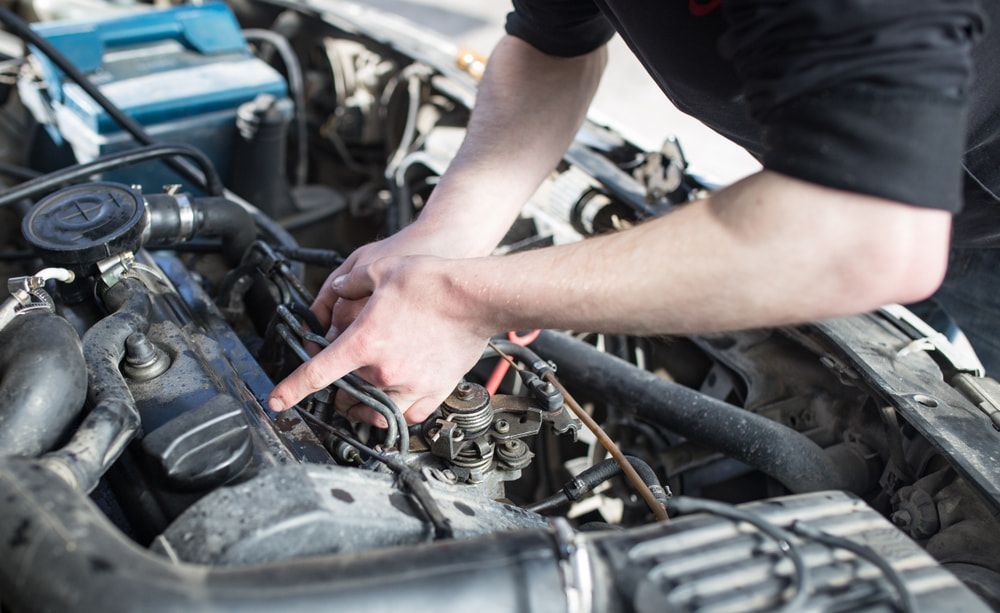 A Man Is Working On The Engine Of A Car — Cameron Brothers Automotive In Currajong, QLD