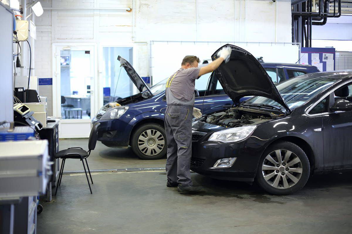 A Man Is Working On A Car In A Garage With The Hood Open — Cameron Brothers Automotive In Currajong, QLD