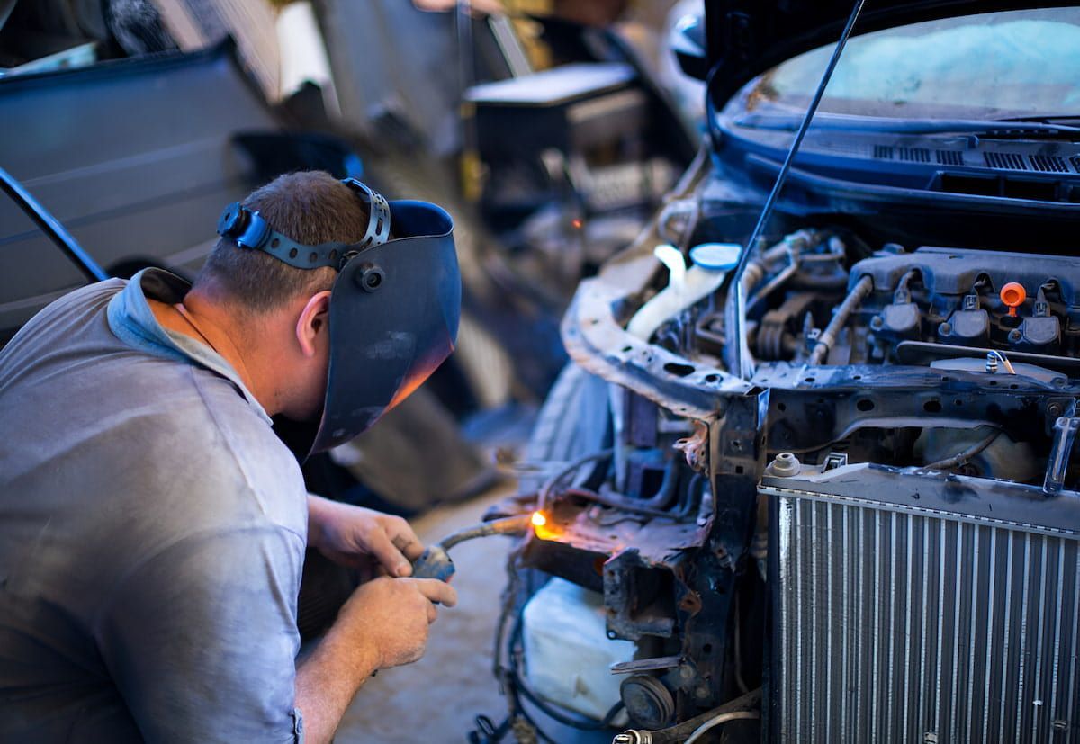 A Man Wearing A Welding Mask Is Working On A Car — Cameron Brothers Automotive In Currajong, QLD