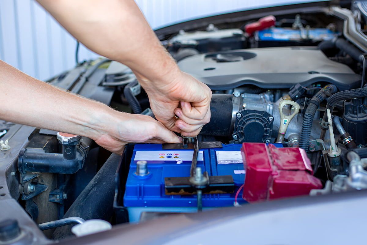 A Person Is Fixing A Car Battery With A Wrench — Cameron Brothers Automotive In Currajong, QLD