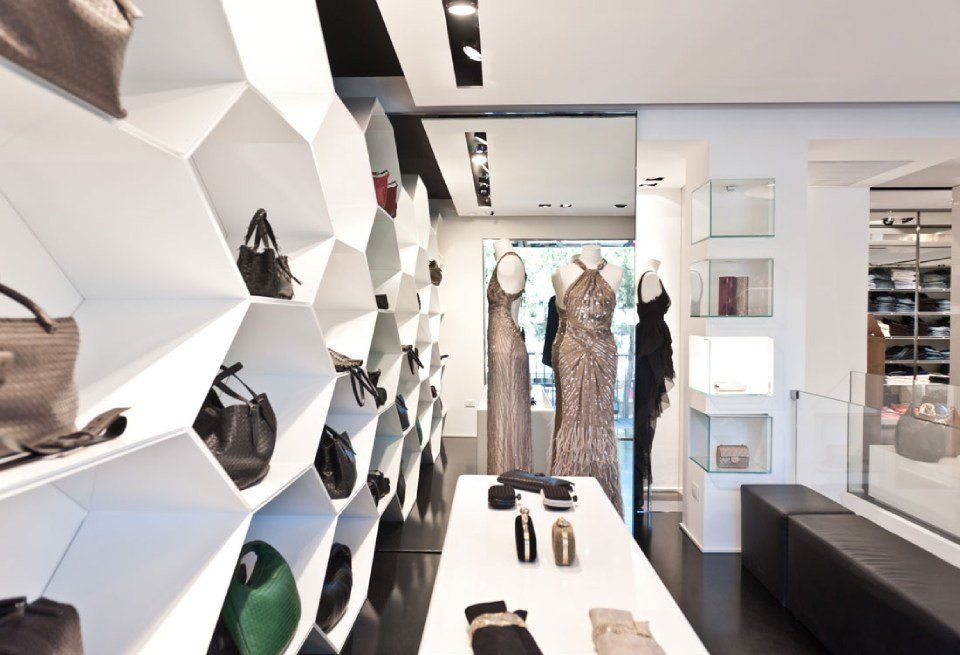 Arredi in legno laccato bianco e in pelle per un elegante negozio di abbigliamento