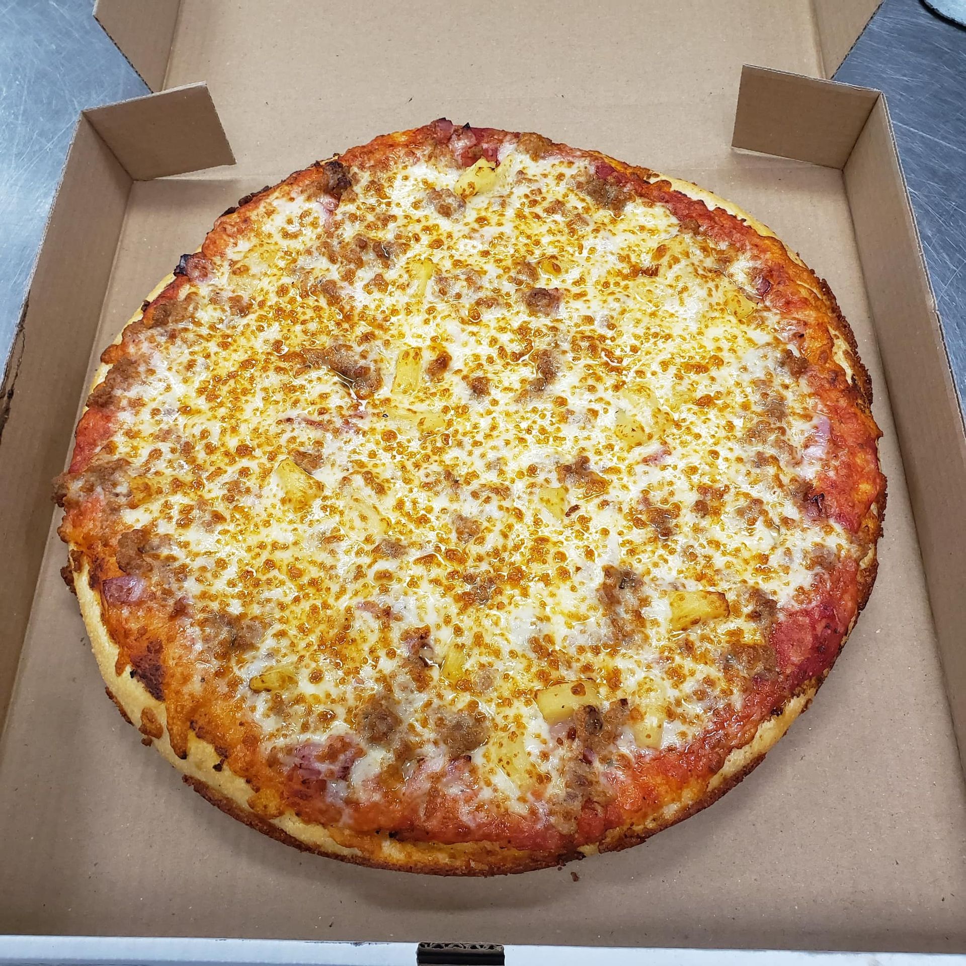 A pizza is sitting in a cardboard box on a table.