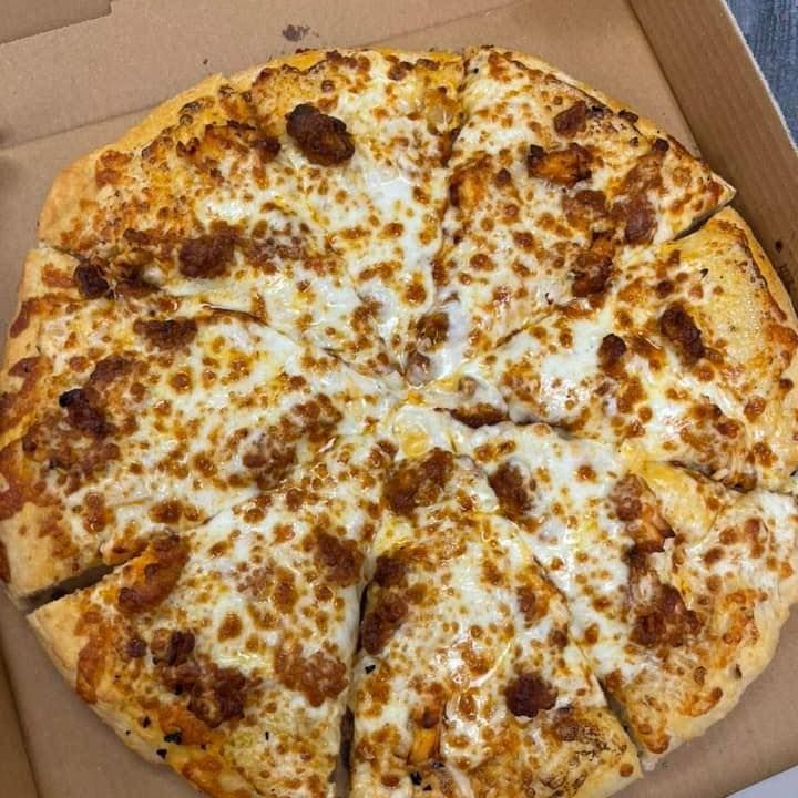 A pizza with a lot of cheese and bacon is in a box.