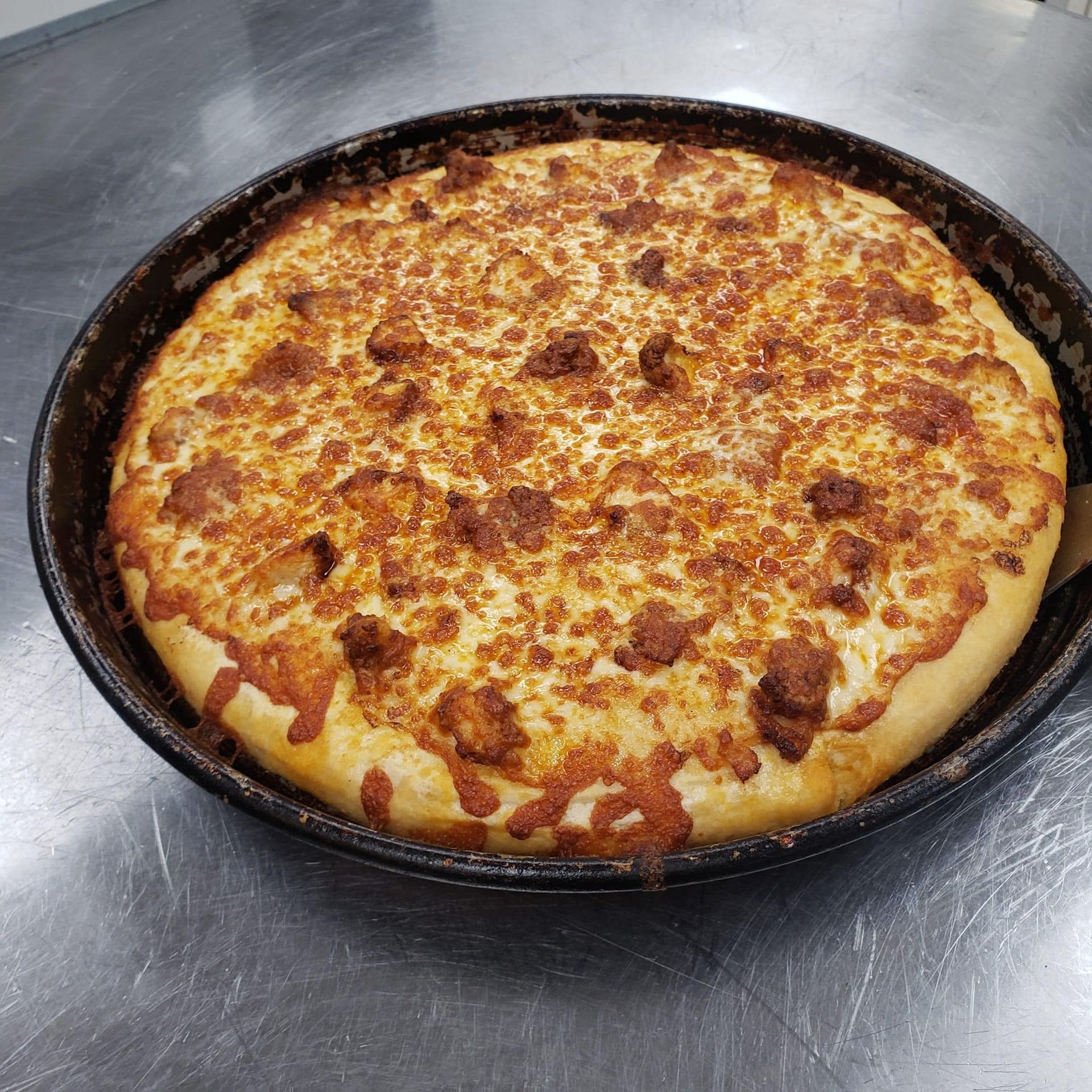 A pizza is sitting in a pan on a table.