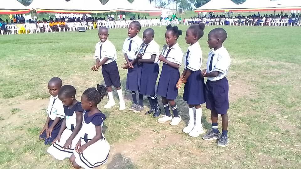 A group of children in school uniforms are standing in a field.