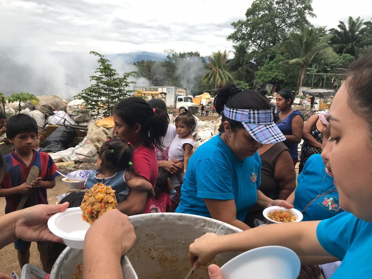 A group of people are standing around a large pot of food.