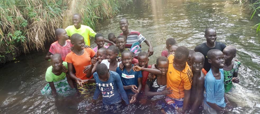 A group of children are standing in a river.