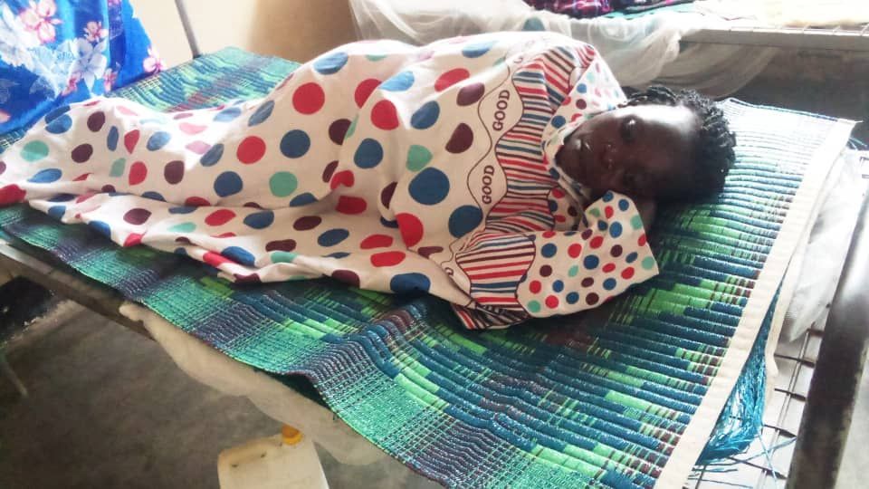 A baby wrapped in a polka dot blanket is laying on a bed.