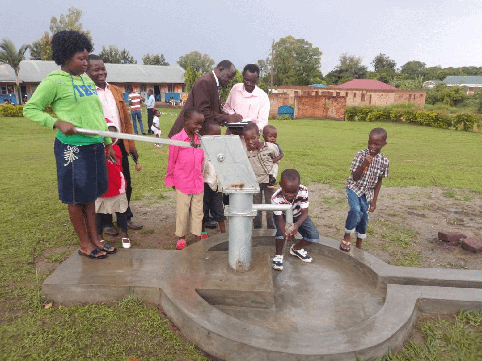 a group of people are standing around a water pump