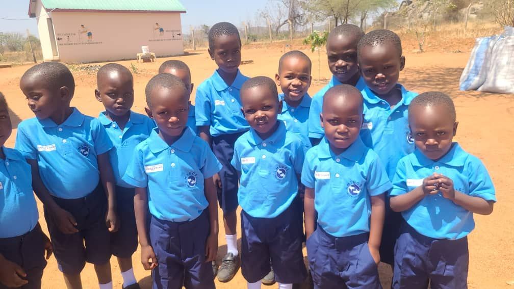 A group of children in blue uniforms are posing for a picture.