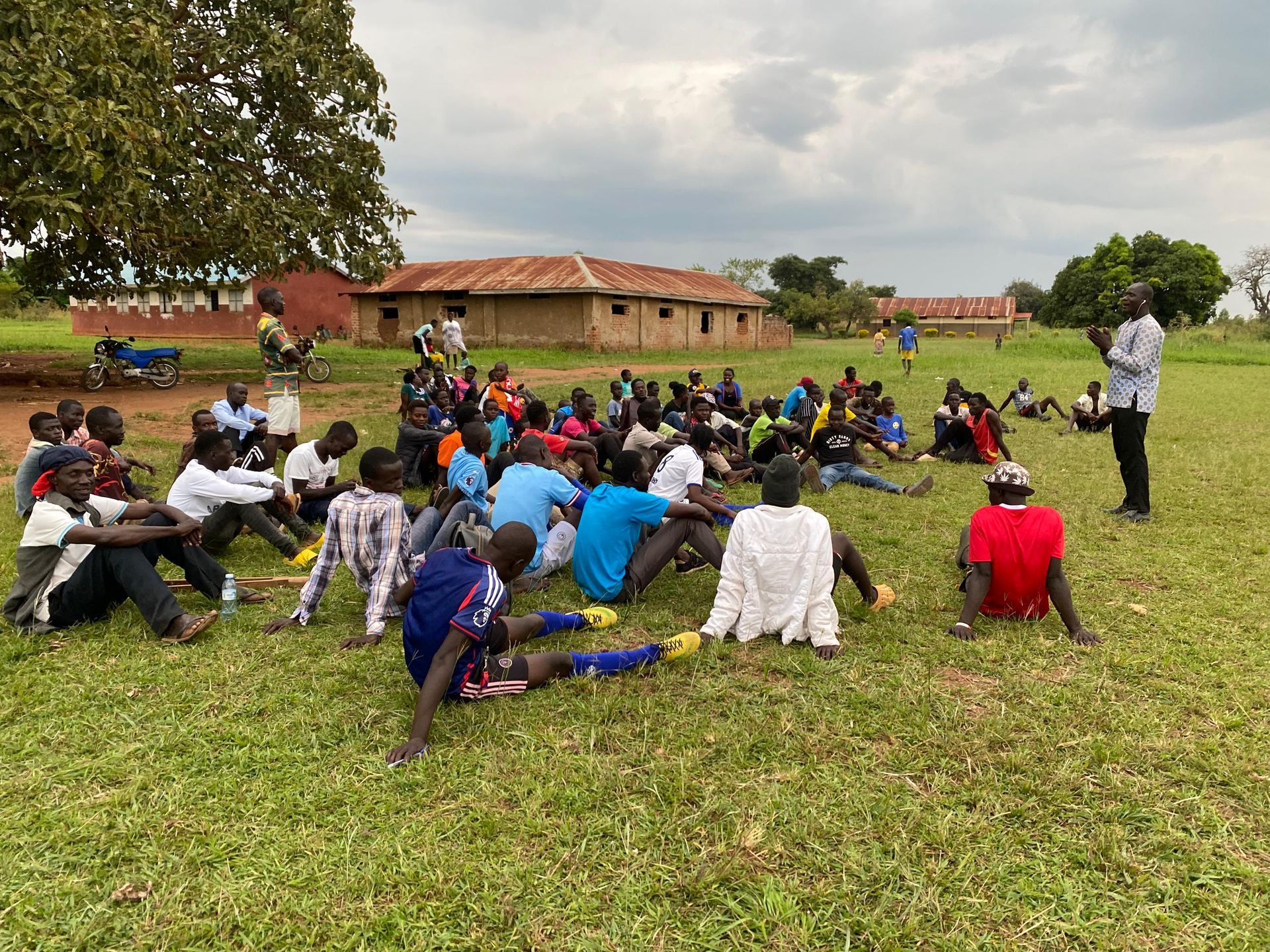 A group of people are sitting on the grass in a field.